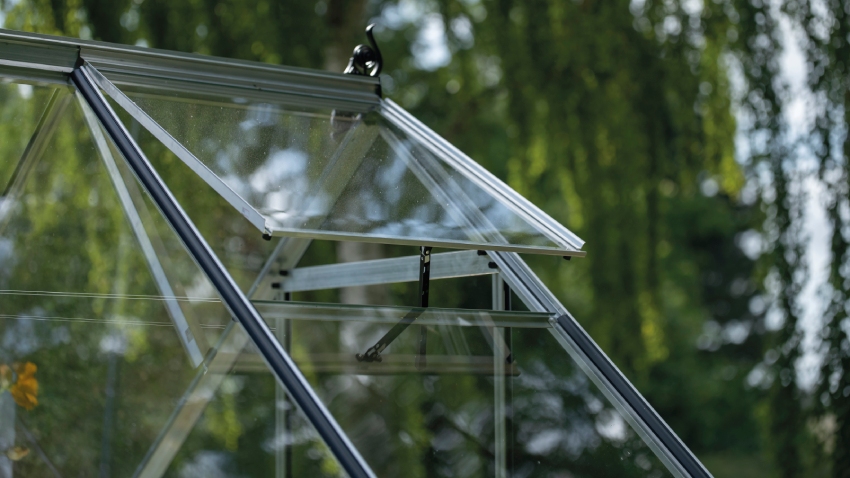 Close-up of Halls ICON 6 6x10 greenhouse roof vent in mill aluminium frame with 3mm toughened glass panel open for ventilation