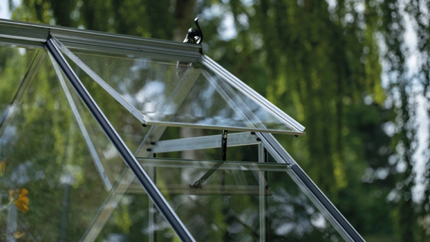 Close-up of Halls ICON 6 greenhouse roof vent in mill aluminium frame with 3mm toughened glass panel open for ventilation