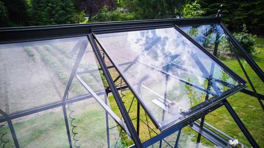 Close-up of Halls ICON 8 8x12 greenhouse roof vent, powder-coated black aluminium frame, and toughened glass panel open for ventilation