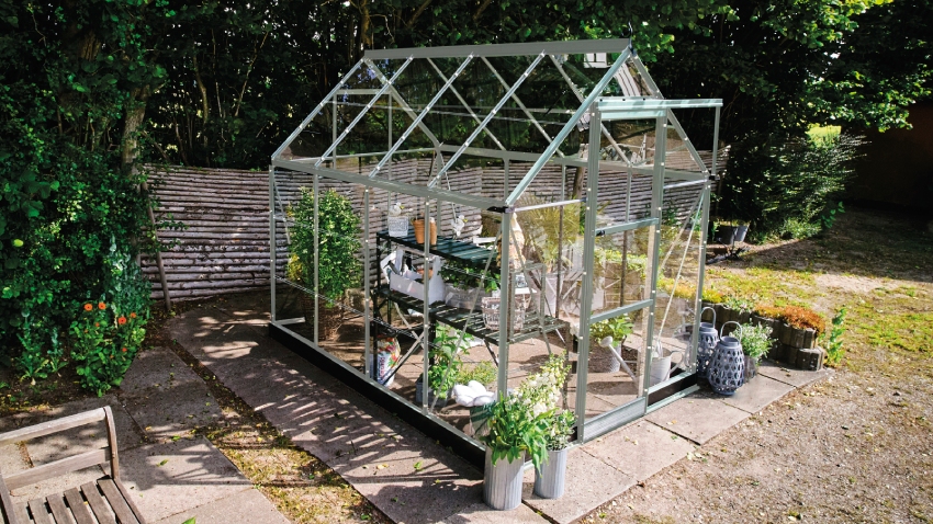 Halls ICON 6 6x8 greenhouse with mill aluminium frame and 3mm horticultural glass installed on patio with staging and plants inside