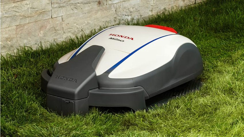 Honda HRM 1000 Miimo robotic lawnmower cutting grass in a domestic garden beside a stone wall