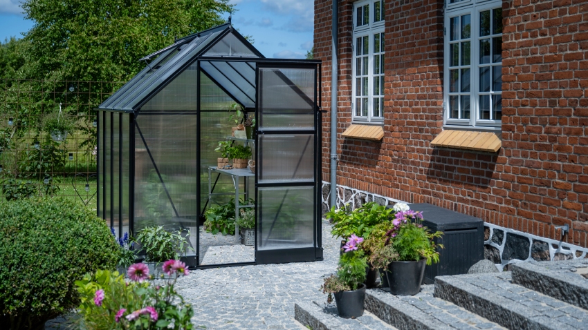 Wide-angled image of the Halls ICON 6 6x8 Greenhouse, with polycarbonate glazing and a powder-coated black aluminium frame.