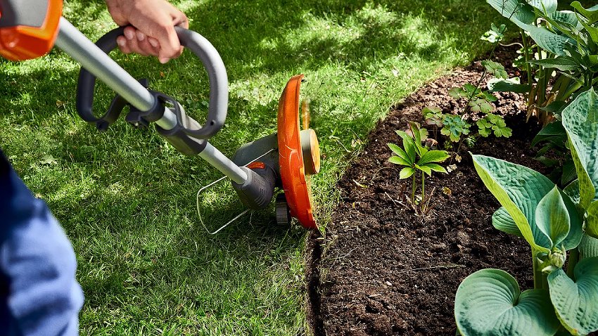 Wide-angled shot of the Husqvarna 110iL FLXi Battery Trimmer tidying up flowerbed borders