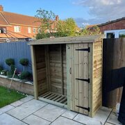 Churnet Valley 6ft x 6ft Log Store with Door & Shelf in a garden