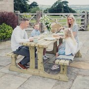 Happy family sat around the Churnet Valley Lunar Wooden Walk-In Picnic Table 150cm enjoying their time together