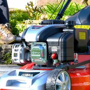 Close-up of Cobra M46SPCVX 46cm self propelled petrol lawnmower showing DG500 131cc OHV engine and primer bulb detail.