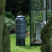 Halls 100L Mini Rainsaver water butt and stand positioned beside a greenhouse on a lawn.