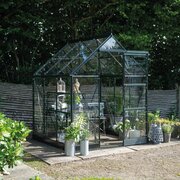 Green Halls Icon 6 6x6 greenhouse with toughened glass, installed on a paved area with potted plants around the entrance. Pre-order and save £287.