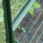 Close-up of the Halls ICON standard louvre kit in green, showing powder-coated aluminium frame and toughened glass blades installed in an ICON greenhouse.