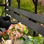 Person folding down the Halls modular folding shelving HR01934 inside an ICON Gardenhouse 8 8x12, demonstrating the space-saving hinged design.