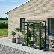 Wide exterior view of the Halls QUBE 62 6x2 black lean-to greenhouse with toughened safety glass, wall-mounted installation, compact footprint, and vertical growing space for herbs and climbing plants.