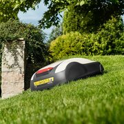 Honda HRM 1000 Miimo robotic lawnmower cutting grass on a sloped garden lawn beside raised stone planters