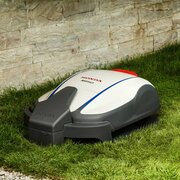 Honda HRM 1000 Miimo robotic lawnmower mowing a domestic garden lawn beside a stone wall