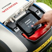 Close-up of the Honda HRM 1000 Miimo robotic lawnmower control panel and stop button interface