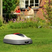Honda HRM 310 Miimo robotic lawnmower mowing a residential garden lawn outside a family home.