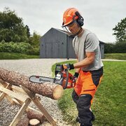 Man wearing chainsaw safety helmet, gloves and protective chaps cutting a log with Husqvarna 435 Mark II petrol chainsaw with 15 inch bar on sawhorse outdoors