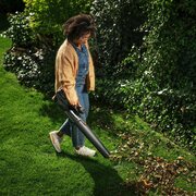 Woman using the Husqvarna Aspire B8X-P4A Leaf Blower to clear leaves in her garden