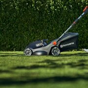 Husqvarna Aspire LC34 Battery Lawnmower Kit cutting grass with somebody pushing it behind