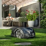 Husqvarna Automower305E NERA operating on a lawn in a garden setting, demonstrating wire-free mowing with EPOS technology.