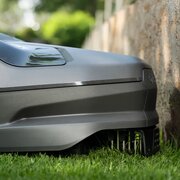 Close-up of the Husqvarna Automower 310E NERA cutting close to a lawn edge, showing wire-free EPOS mowing performance.