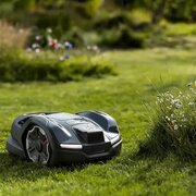 Husqvarna Automower 405XE NERA robotic mower cutting lawn edge beside wildflower border using EdgeCut technology