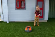 A little girl playing with the Husqvarna Battery-Powered Toy Automower in her garden
