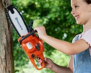 Little girl pretending to cut a tree with the Husqvarna Toy Chainsaw Kit