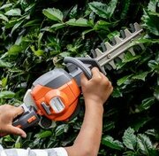 Little hands holding the Husqvarna Toy Hedge Trimmer, roleplaying a spot of topiary