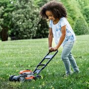 Young child pushing the Husqvarna Toy Lawnmower across grass during outdoor pretend garden play