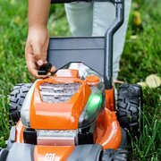 Child activating the realistic starter on the Husqvarna Toy Lawnmower with illuminated lights and detailed controls