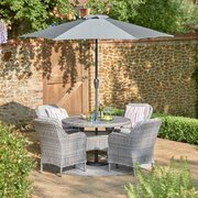LG St Tropez Stone 4 Seat Garden Dining Set with round table, four cushioned armchairs and 2.5m parasol, shown on a summer's day.