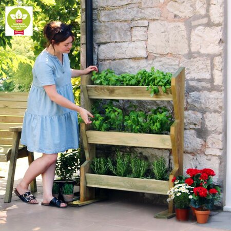 Woman enjoying her Vertical Herb Stand filled with plants and veg