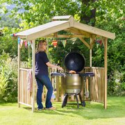 Person cooking on a barbecue under the Zest Ashton BBQ Shelter wooden garden BBQ canopy with roof vent